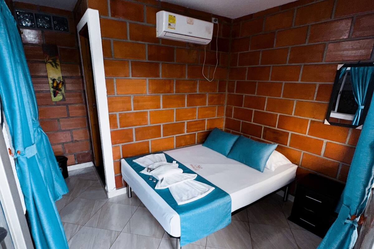 A room with a bed, a brick wall, and a tiled floor.
