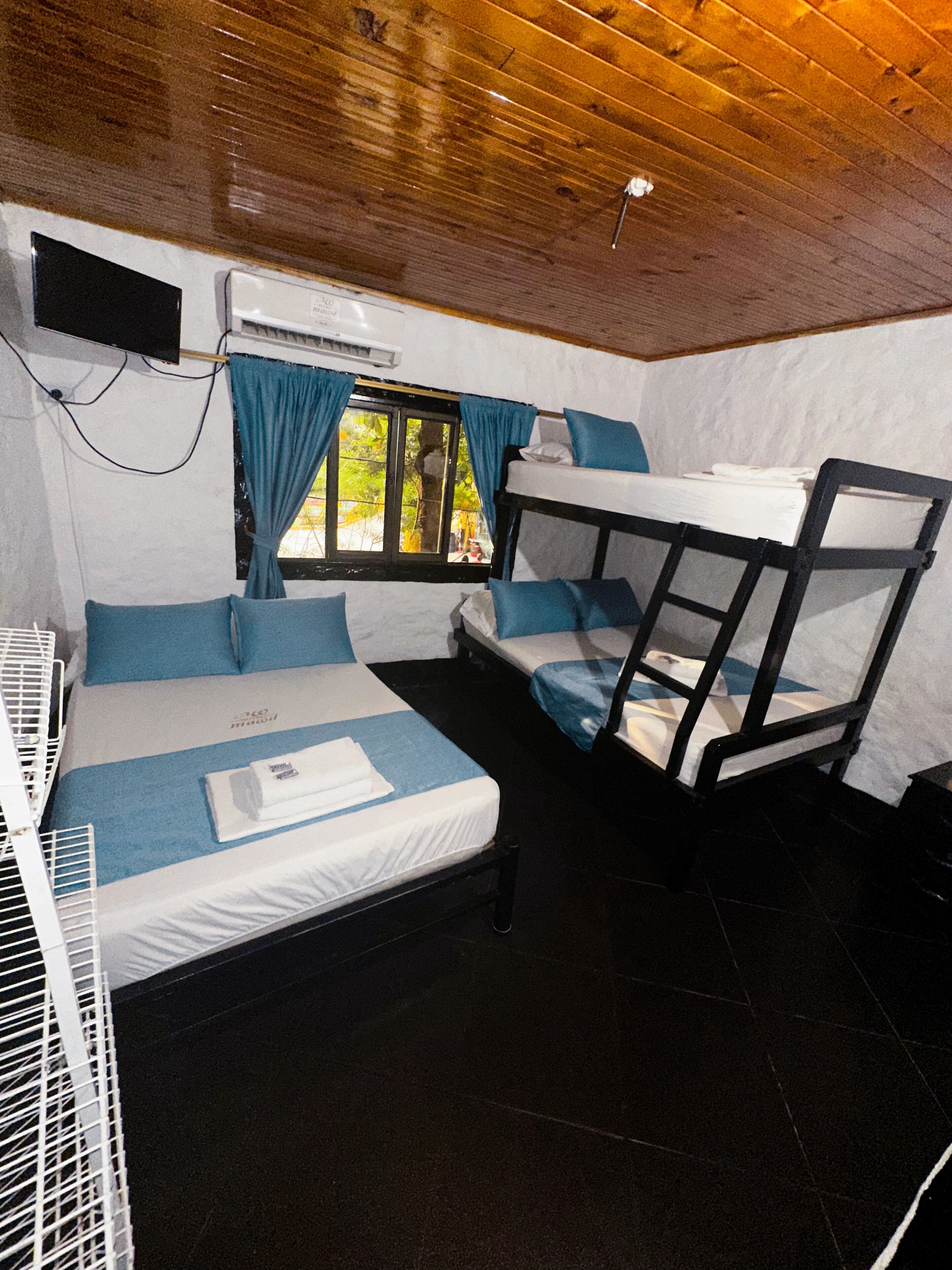 A compact room with bunk beds, a small table, and a window with curtains.