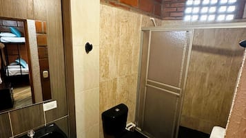 Un baño pequeño con lavamanos, inodoro y cabina de ducha.