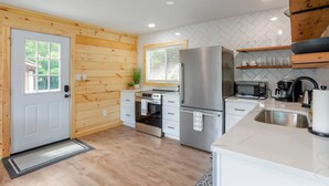 Une cuisine moderne avec des murs en bois, un réfrigérateur en acier inoxydable, un four à micro-ondes et un évier.