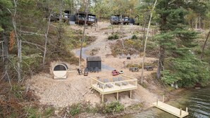Un ensemble de chalets situés au bord du lac, avec un espace extérieur aménagé pour s’asseoir, une terrasse en bois et un petit quai.