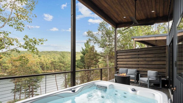 Un bain à remous sur un balcon avec vue sur une forêt et un lac.
