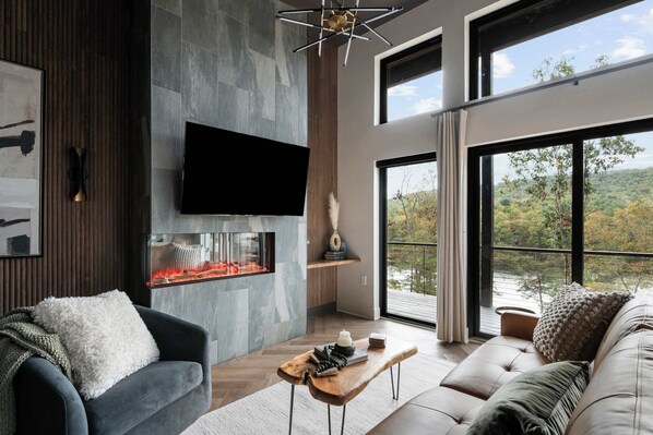 Una sala de estar moderna con chimenea, ventanas amplias y un televisor de pantalla plana.