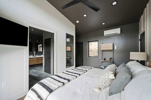 Un dormitorio moderno con una cama grande, un televisor montado en la pared y un vestidor.