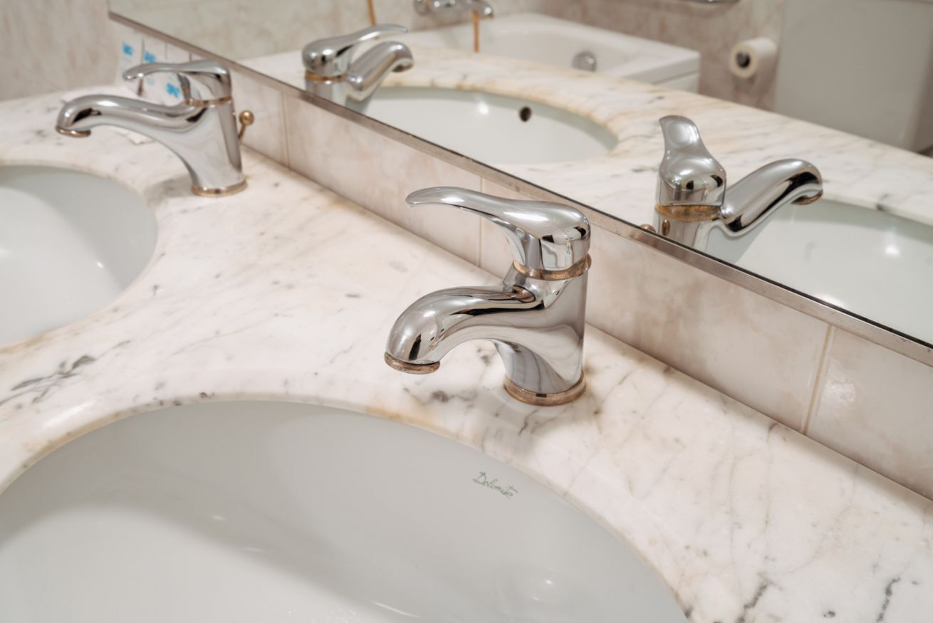 A bathroom with two sinks, each with a chrome faucet, and a large mirror above them.