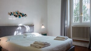 Un lit bien fait, avec des serviettes pliées, une lampe de chevet et une fenêtre avec des rideaux.