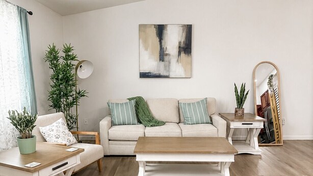 En stue med sofa, sofabord og en potteplante.