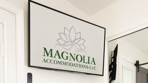 Et indrammet skilt med en lotusblomst og teksten "Magnolia Accommodations-11C" på en hvid væg.