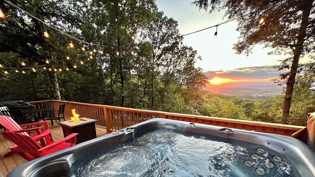 A hot tub on a deck with a sunset view, surrounded by trees and string lights. - Mountain View Cabin~HotTub~Fireplace~King Bed (New Market)