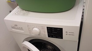 Eine Waschmaschine mit Frontlader und einem grünen Korb darauf.