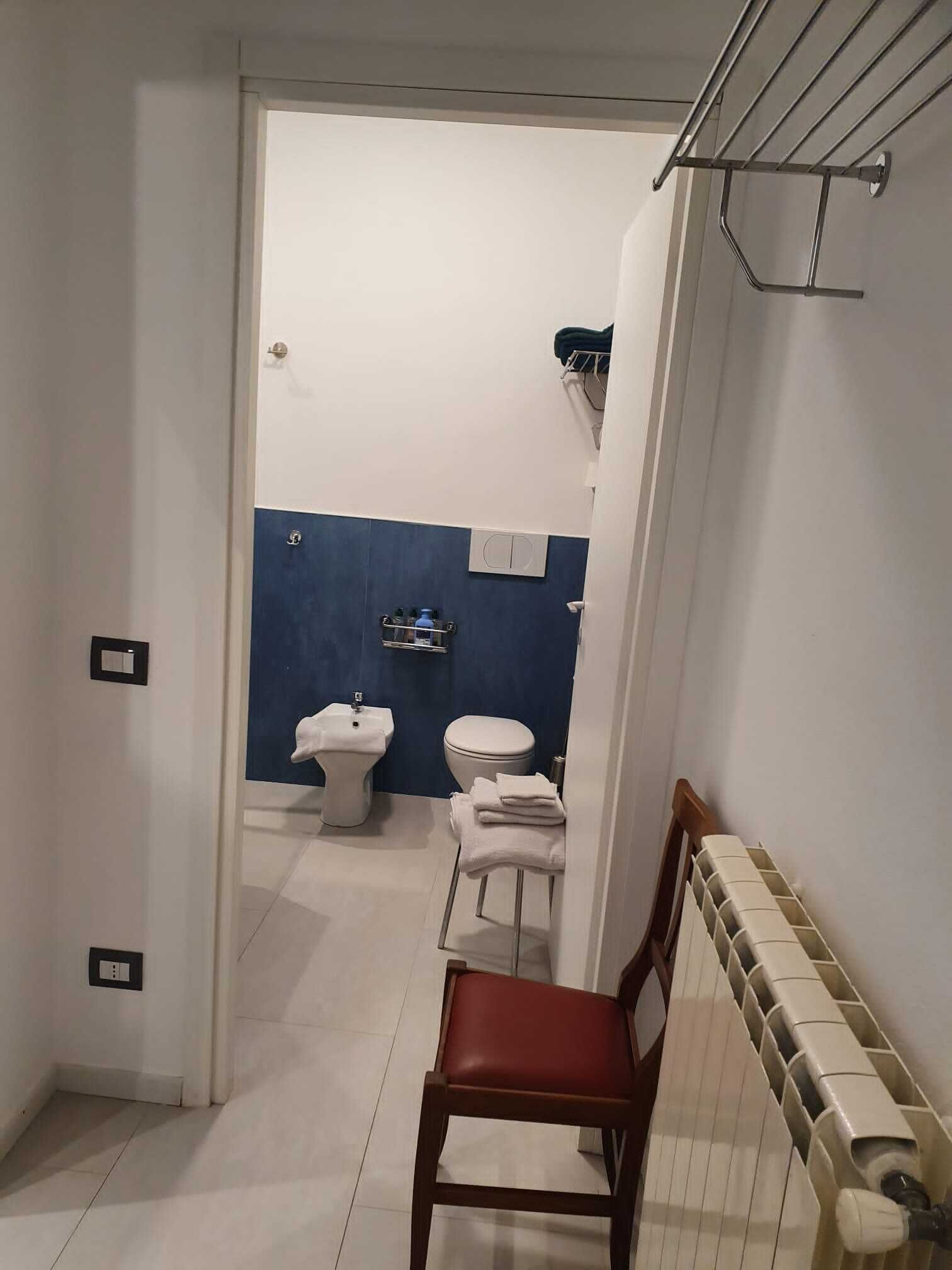 Et badeværelse med toilet, bidet og et håndklædestativ.