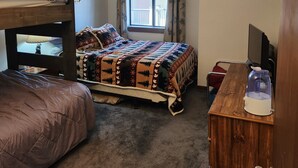 Un dormitorio con literas, un escritorio, una silla, una ventana con cortinas y un radiador.