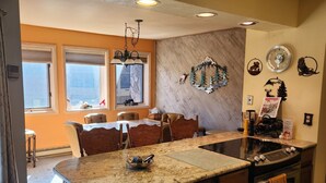 Una cocina moderna con una isla central, horno empotrado y un comedor con mesa y sillas.