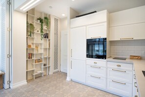 A modern kitchen with white cabinetry, a built-in oven, and a decorative plant shelf.