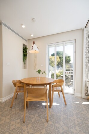 Un comedor con una mesa redonda de madera, seis sillas, una lámpara colgante y vistas a un patio exterior a través de un ventanal.
