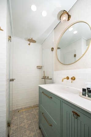A bathroom with a shower, a sink with a mirror, and a vanity with drawers.
