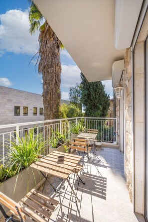 A balcony with a table and chairs, potted plants, and a view of the cityscape.