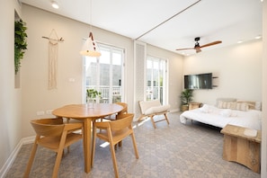 A modern living room with a round wooden table, a sofa, and a TV mounted on the wall.
