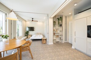 A modern hotel room with a bed, a TV, a ceiling fan, a dining area with a table and chairs, and a built-in bookshelf. - Exclusive&Lovely Apartment in Prestigious Talbiya (Jerusalem)