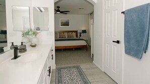 Une salle de bain moderne avec un meuble-lavabo blanc, un grand miroir et un ventilateur de plafond.