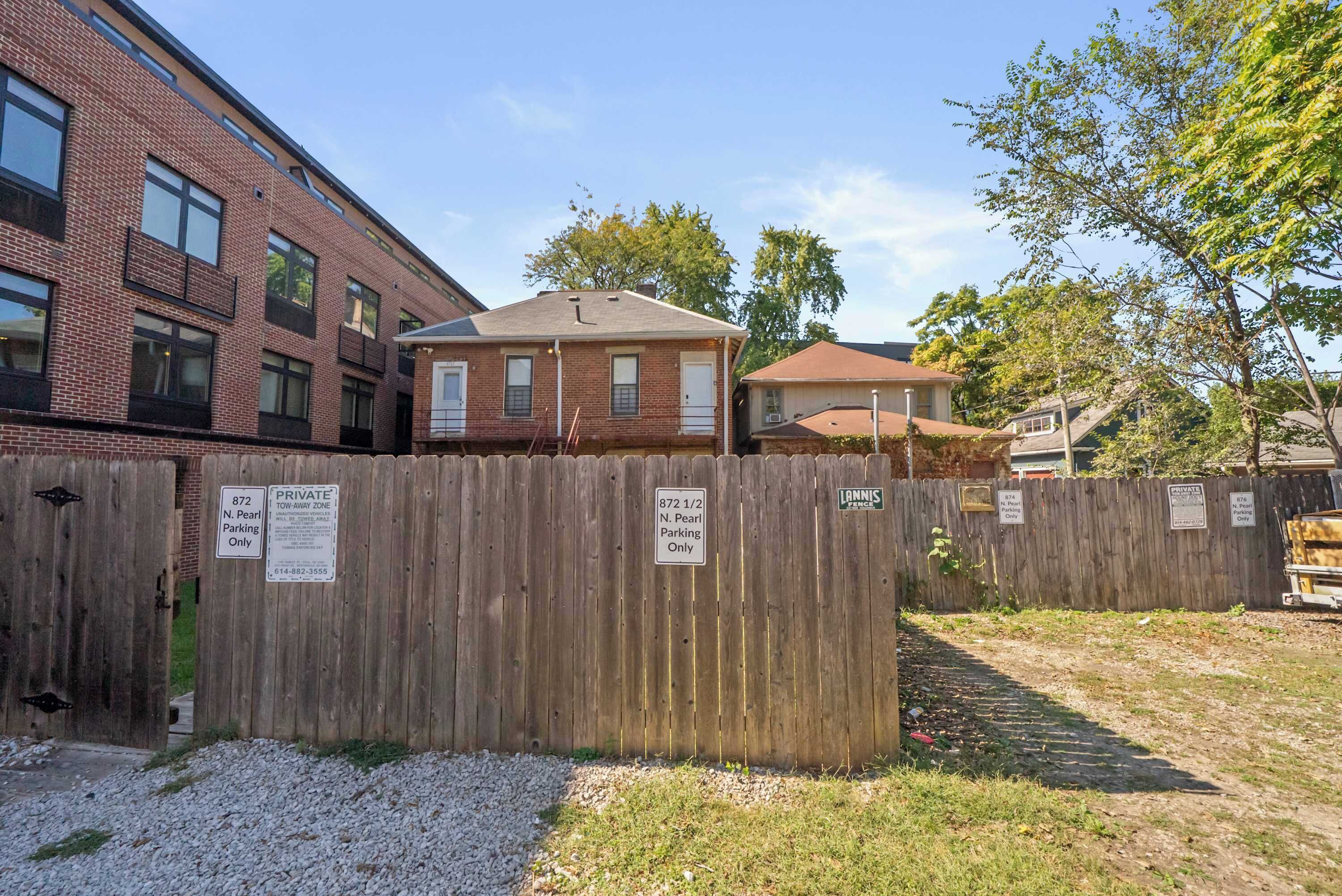 A fenced residential area with a brick building and a detached house.