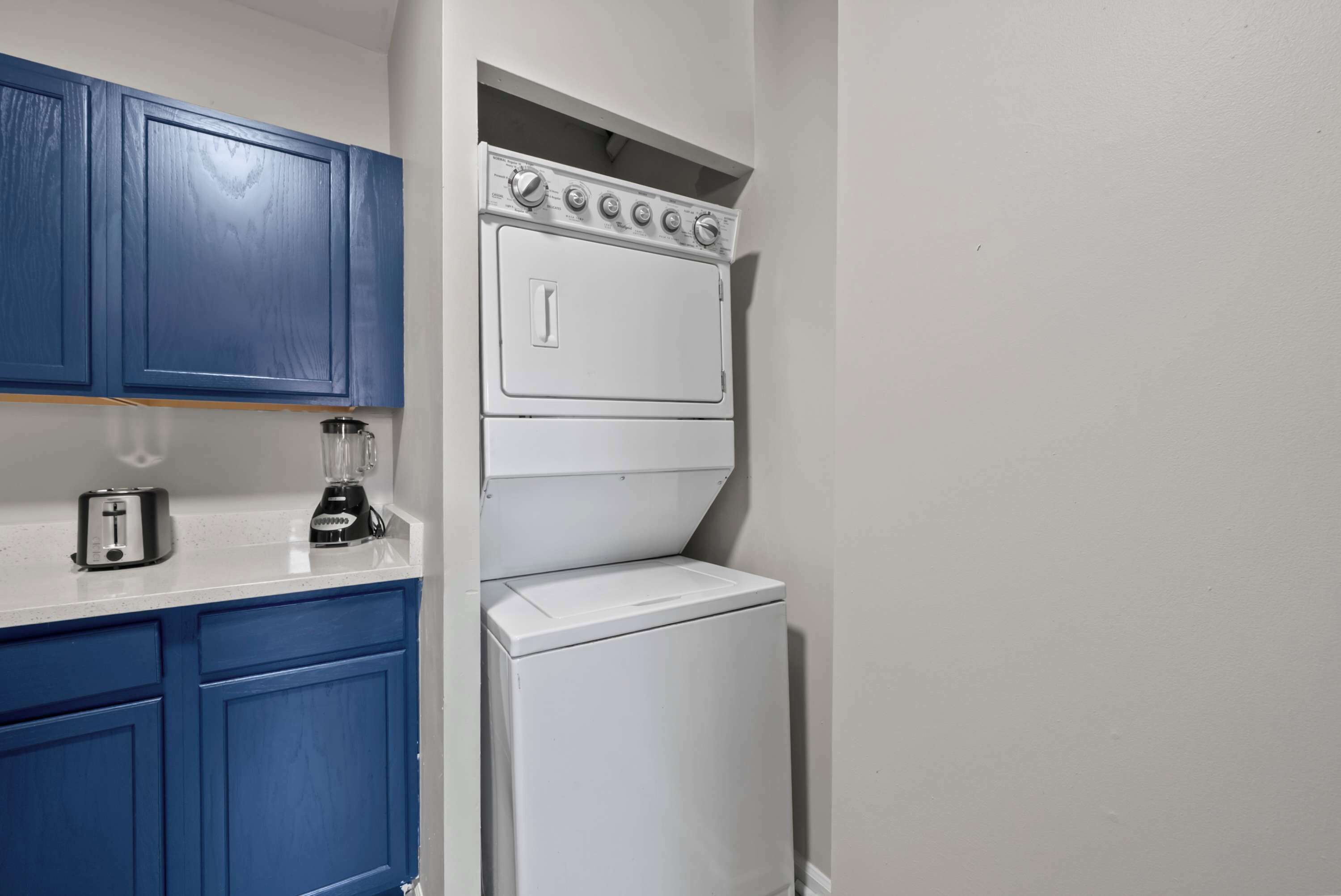 Una cocina compacta con armarios azules, una estufa blanca, un tostador y una licuadora.