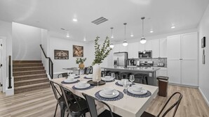 Una cocina moderna con armarios blancos, horno empotrado y refrigerador de acero inoxidable.