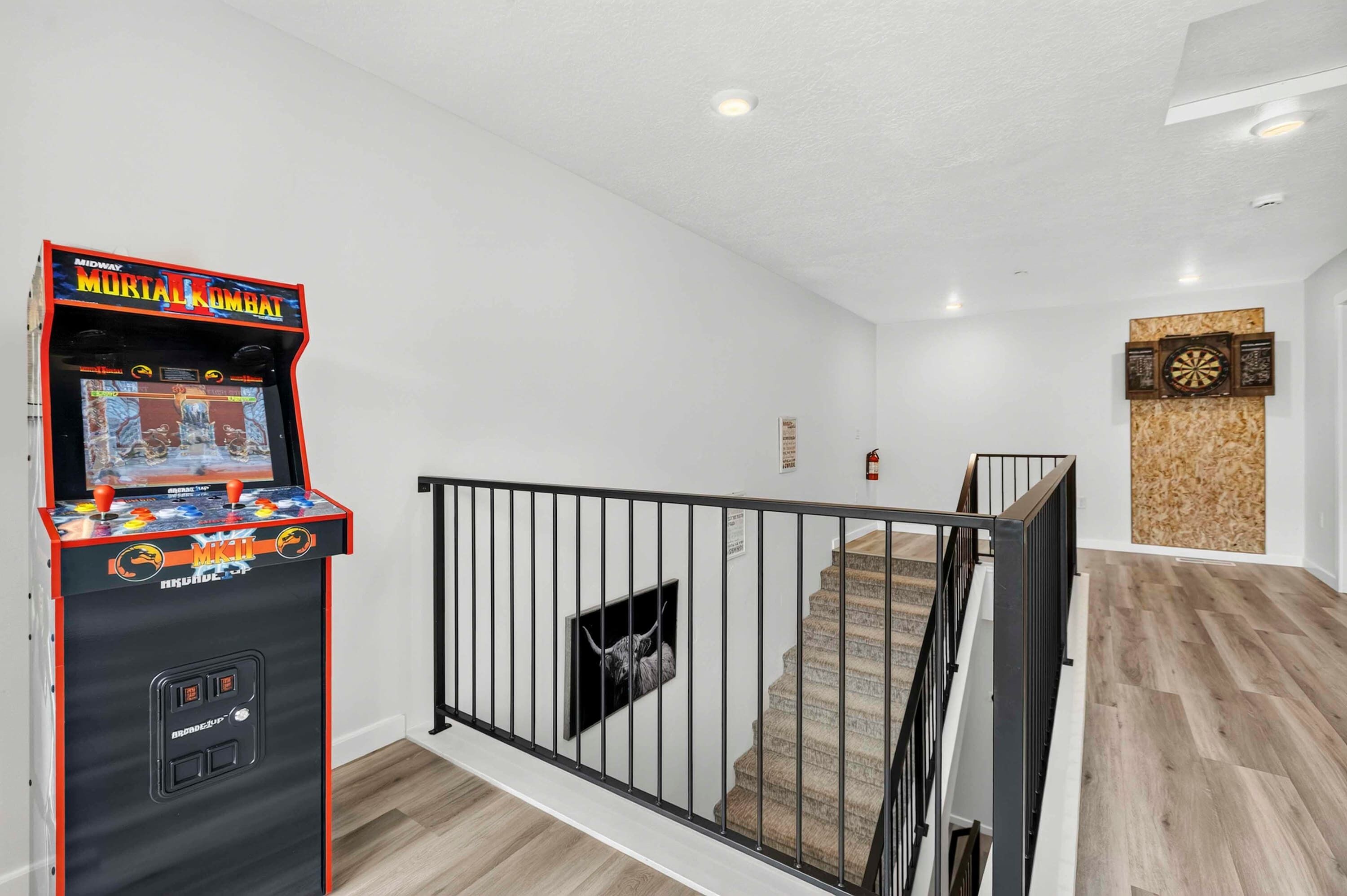 Een kamer met een gameconsole, een trap en een dartbord.