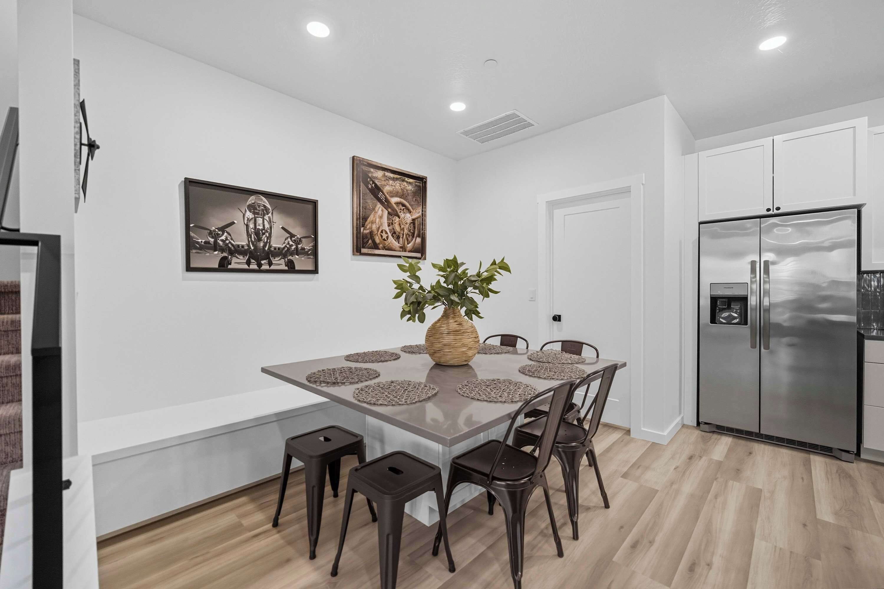 A modern kitchen with a central island, white cabinetry, and a stainless steel refrigerator.
