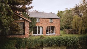 A brick house with a sloped roof, large windows, and a small porch.