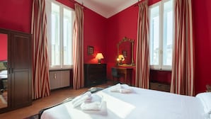 Una habitación de hotel con una cama, dos mesitas de noche, un espejo y una ventana con cortinas.