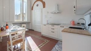 Una cocina con armarios blancos, encimera de madera, una ventana y una puerta.