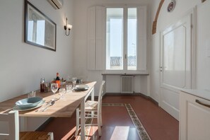 A dining area with a table set for four, a radiator, and a window with a view. - Scale 50 Apartament (Firenze)