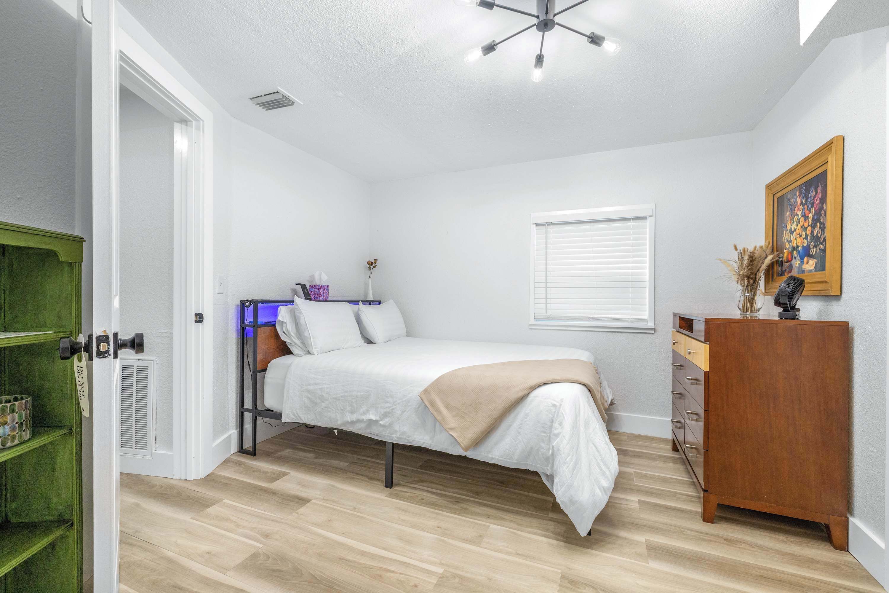A bedroom with a bed, dresser, and a green door.