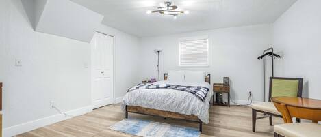 Un dormitorio con una cama, un escritorio, una silla y una lámpara en el techo.
