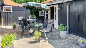An outdoor patio with a table and chairs, surrounded by potted plants and a covered umbrella. - 1 bedroom lovely home in Vig (Vig)