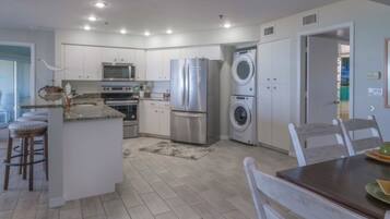 A modern kitchen with stainless steel appliances, a central island, and a dining area with a table and chairs.