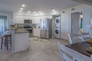 A modern kitchen with stainless steel appliances, a central island, and a dining area with a table and chairs.