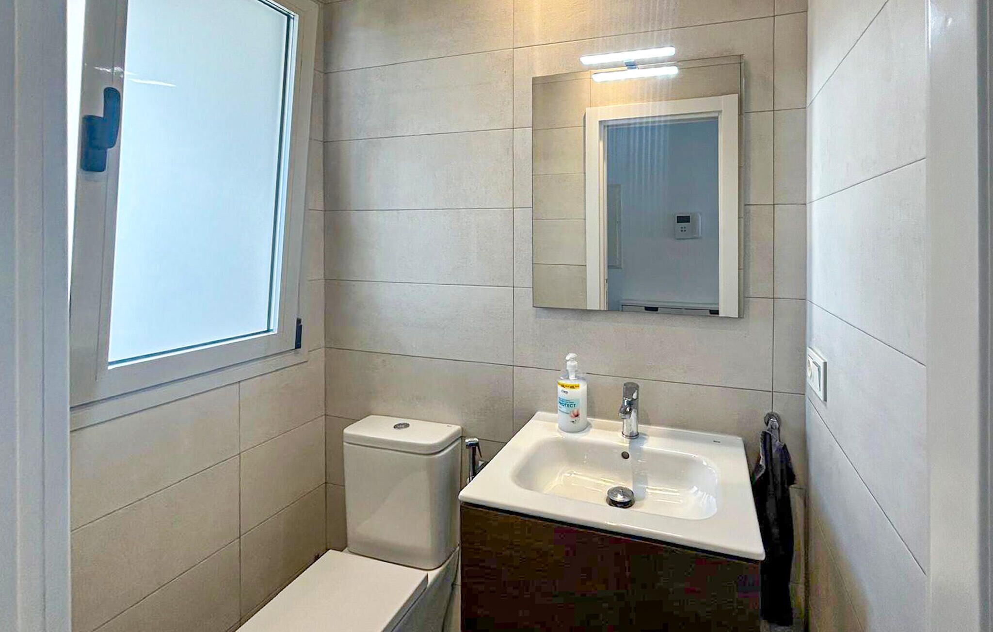 A small bathroom with a toilet, sink, and mirror.