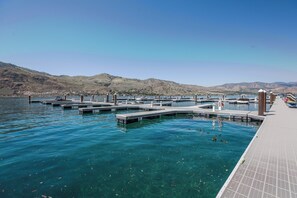 A marina with docks extending into calm water, surrounded by hills.