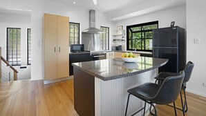 Een moderne keuken met een centraal eiland, roestvrijstalen apparatuur en een groot raam voor natuurlijk licht.
