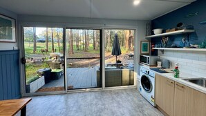 Une cuisine moderne dotée d’une grande porte-fenêtre coulissante donnant sur une terrasse, ainsi que d’un lave-linge et d’un four à micro-ondes.