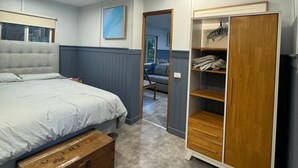 Une chambre à coucher avec un lit, une armoire, un ventilateur de plafond et une vue sur une autre pièce.