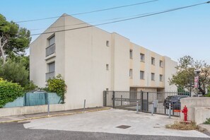 Un bâtiment moderne doté d’une entrée sécurisée par un portail, d’une borne d’incendie et surplombant un ciel dégagé.