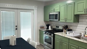 A modern kitchen with green cabinets, a stainless steel stove, and a microwave. - Stylish Apt: 20 Min to Manhattan, Groups (West New York)