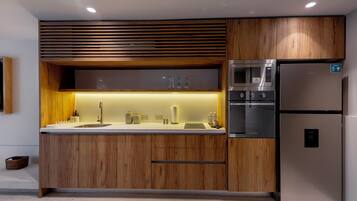 A modern kitchen with wooden cabinets, a stainless steel refrigerator, and built-in appliances.