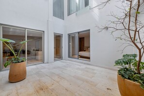 A spacious indoor area with large windows, a tiled floor, and potted plants. - Capitalia Reforma Chapultepec (Mexico City)
