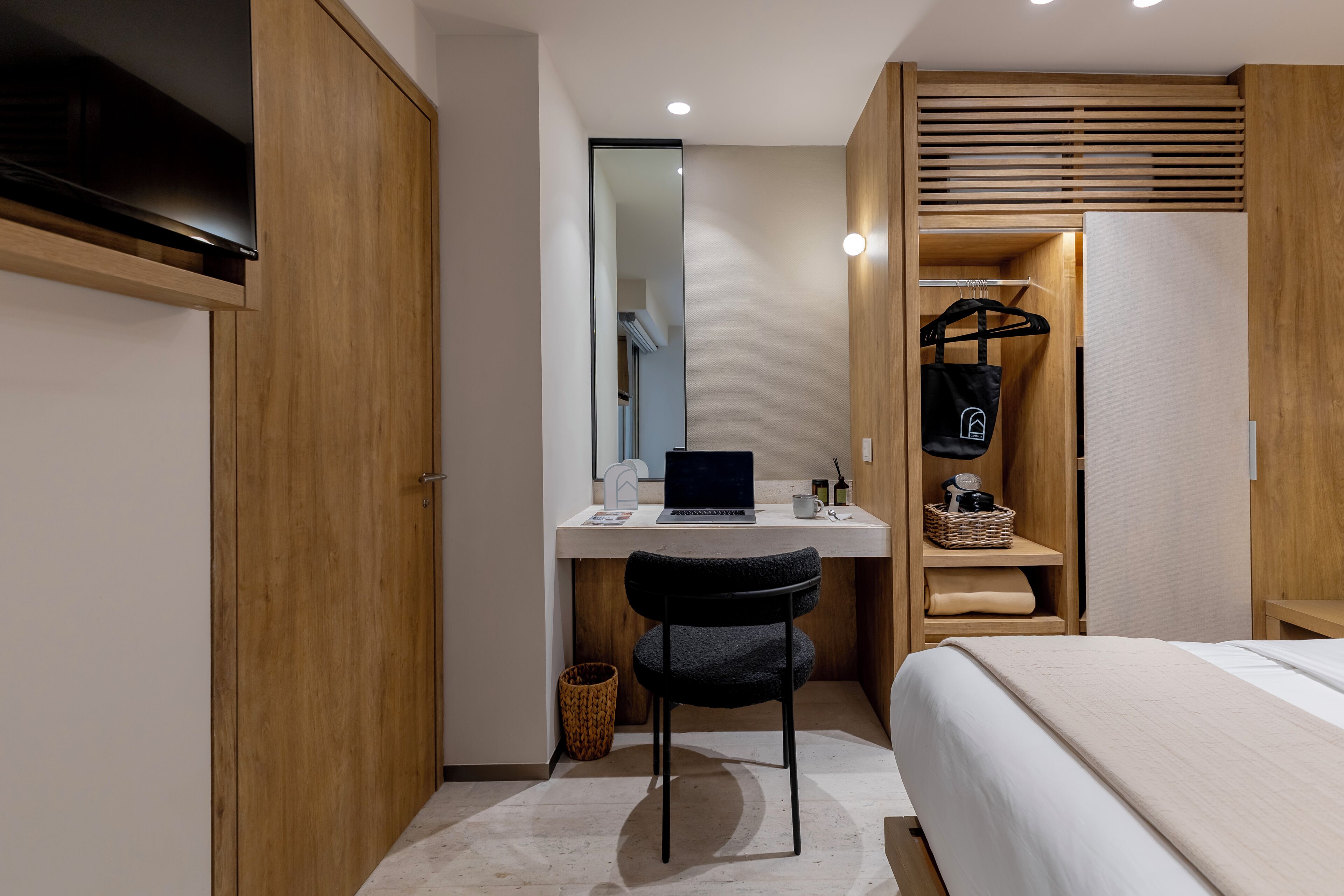 Une chambre moderne avec une armoire en bois, un bureau avec un ordinateur portable, une chaise, un lit et un étendoir à linge.