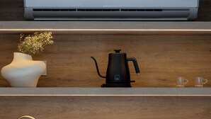 Una cucina moderna con aria condizionata integrata, una macchina per caffè, un vaso con fiori e un lavandino.