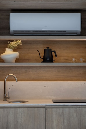 A modern kitchen with a built-in air conditioner, a coffee maker, a vase with flowers, and a sink. - Capitalia Reforma Chapultepec (Mexico City)